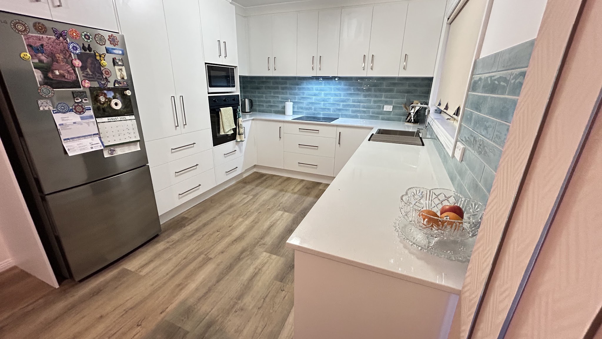 White kitchen with a pale blue subway splashback and full height pantry cabinetry